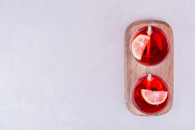 Dois copos de suco vermelho em uma placa de madeira