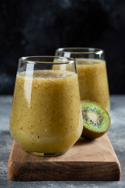 Foto grátis dois copos de vidro de suco de kiwi na placa de madeira.