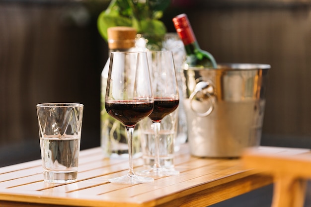 Foto grátis dois copos de vinho tinto e copo de água na mesa de madeira