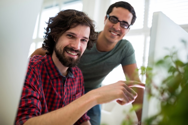 Dois designers gráficos masculinos interagindo sobre o computador