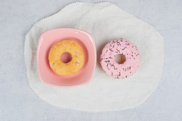 Dois donuts com aspersores na mesa de mármore. Foto de alta qualidade