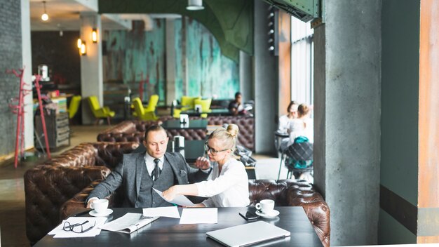 Dois empresários sentados juntos, verificando o documento no café