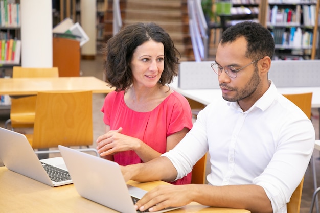 Foto grátis dois estudantes universitários adultos conversando enquanto trabalhava