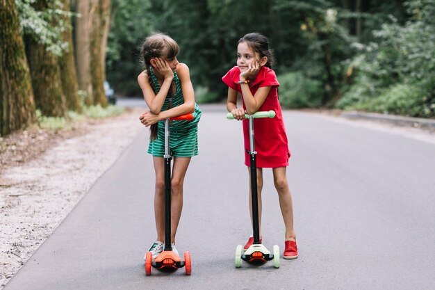 Dois, femininas, amigos, ficar, com, empurre scooter, ligado, rua