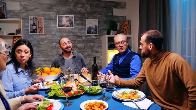 Dois filhos conversando com o pai no jantar. comida deliciosa.