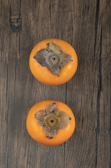 Dois frutos de caqui maduros colocados em superfície de madeira