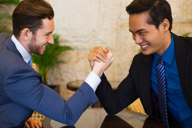 Dois homens de negócios arm wrestling obstinadamente no lobby