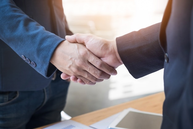 Dois homens de negócios confiantes apertando as mãos durante uma reunião no escritório, sucesso, trato, saudação e conceito de parceiro