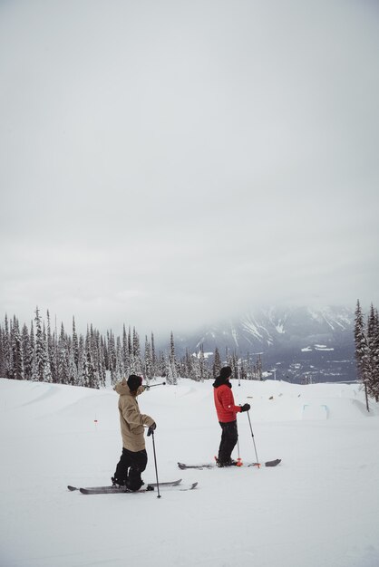 Dois homens esquiando em montanhas nevadas na estação de esqui