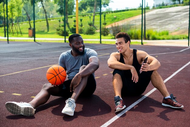 Dois homens sentados na quadra de basquete