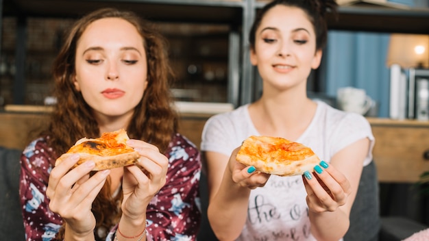 Dois, jovem, femininas, amigos, segurando, fatia pizza