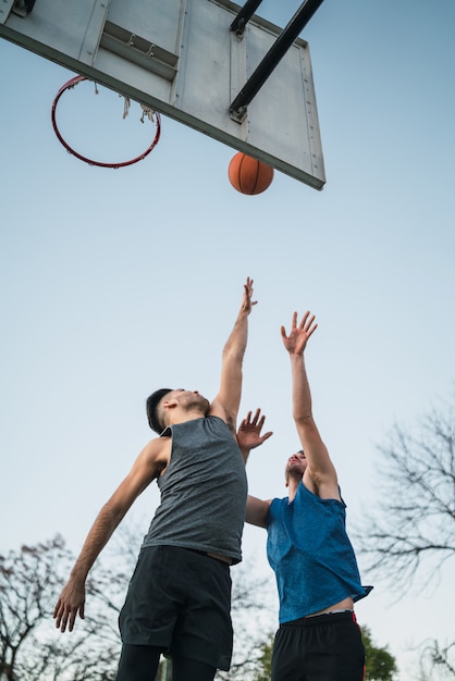 Dois jovens amigos jogando basquete.