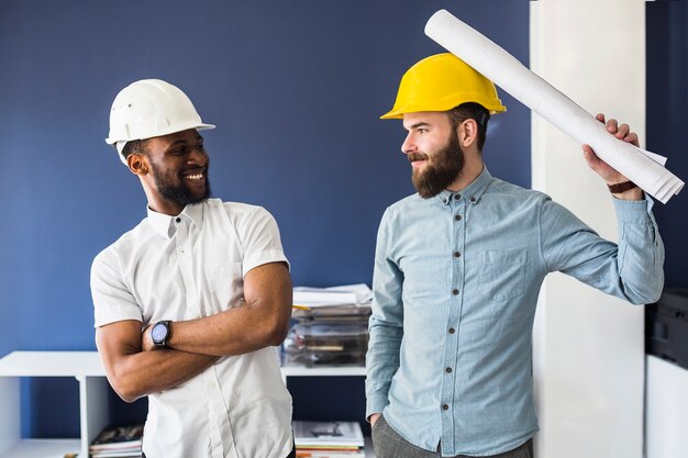 Dois jovens arquitectos masculinos felizes tirando sarro no escritório