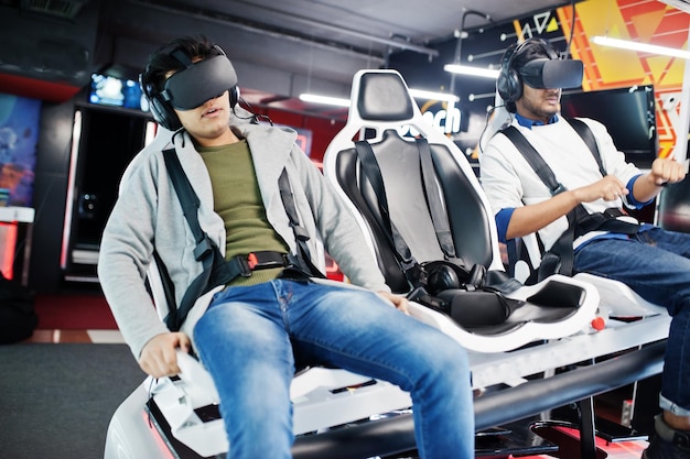 Dois jovens indianos se divertindo com uma nova tecnologia de um fone de ouvido vr no simulador de realidade virtual