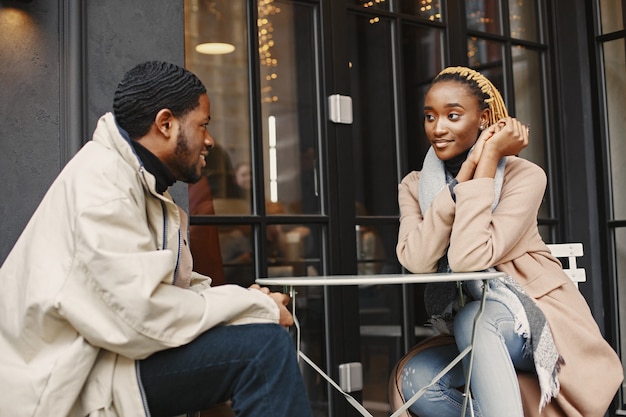 Dois jovens sentados do lado de fora. Casal africano, aproveitando o tempo que passa um com o outro.