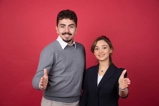 Dois jovens trabalhadores de escritório oferecendo suas mãos para um aperto de mão