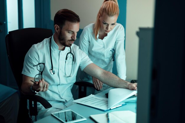 Dois médicos cooperando ao analisar dados médicos de um paciente no hospital