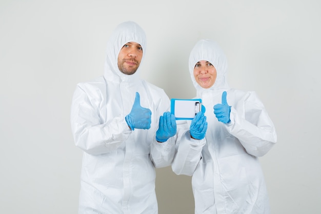 Dois médicos em traje de proteção, luvas segurando uma mini prancheta