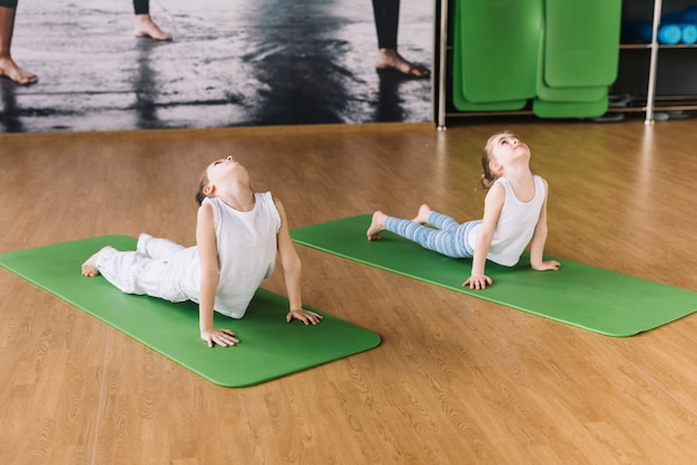 Dois, menina saudável, exercitar, ligado, tapete verde, sobre, escrivaninha madeira