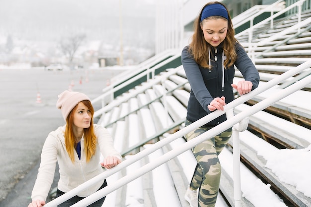 Dois, mulheres jovens, esticar, bleacher, em, inverno