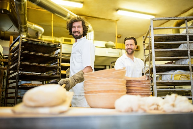Dois padeiros sorriso que prepara o pão na cozinha da padaria