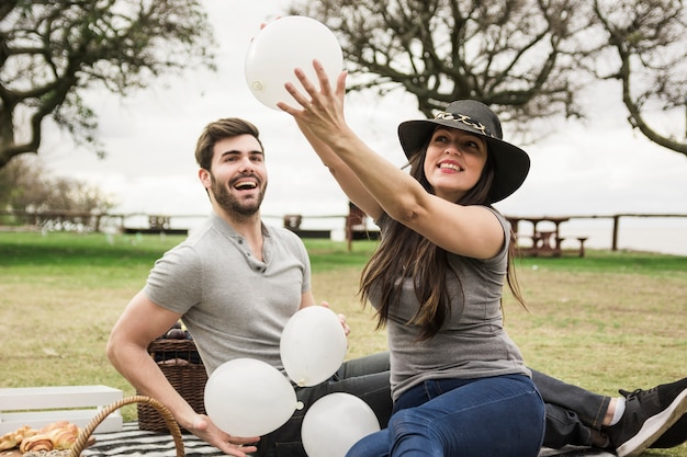 Dois, par jovem, tocando, com, balões brancos, parque