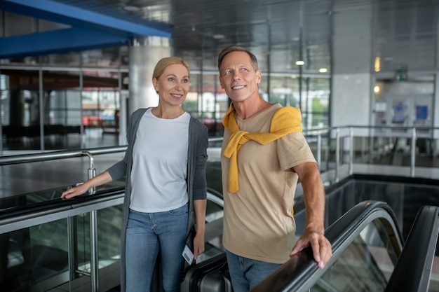 Dois passageiros saindo da escada rolante do aeroporto