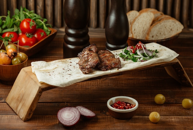 Dois pedaços de bifes servidos em lavash com espécies