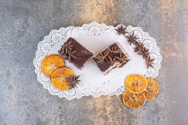 Dois pedaços de bolos com laranja seca e anis estrelados na superfície branca