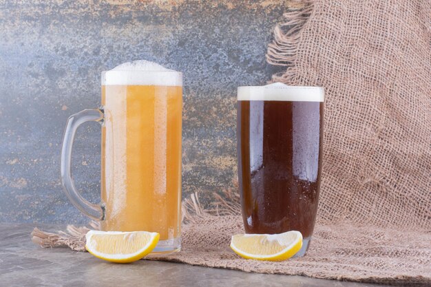 Dois tipos de cervejas na mesa de mármore com limões. Foto de alta qualidade