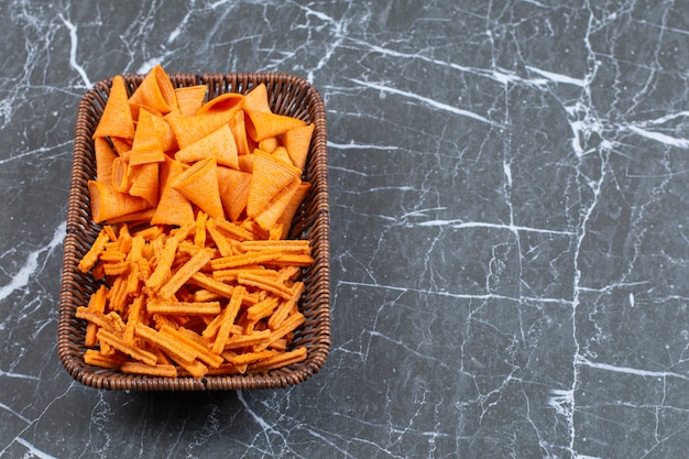 Dois tipos de chips crocantes na cesta de madeira.