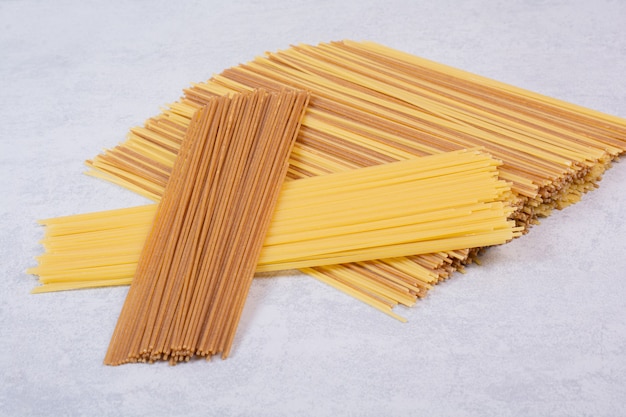 Dois tipos de macarrão espaguete cru na superfície branca