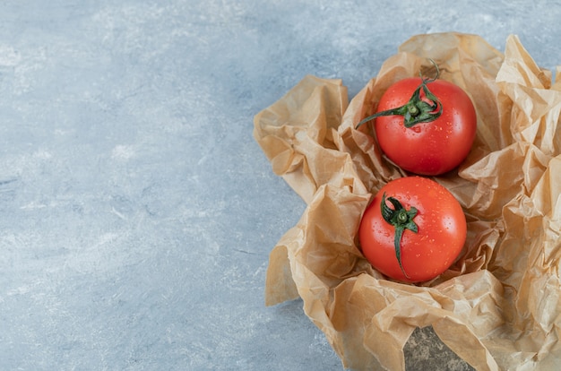 Dois tomates inteiros frescos em um papel manteiga.