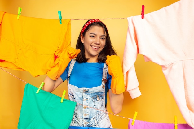 Foto grátis dona de casa linda e divertida fazendo trabalhos domésticos isolada no espaço amarelo