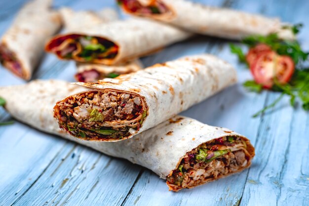 Doner de frango vista lateral com cebola pepino alface e molho em pão árabe em cima da mesa