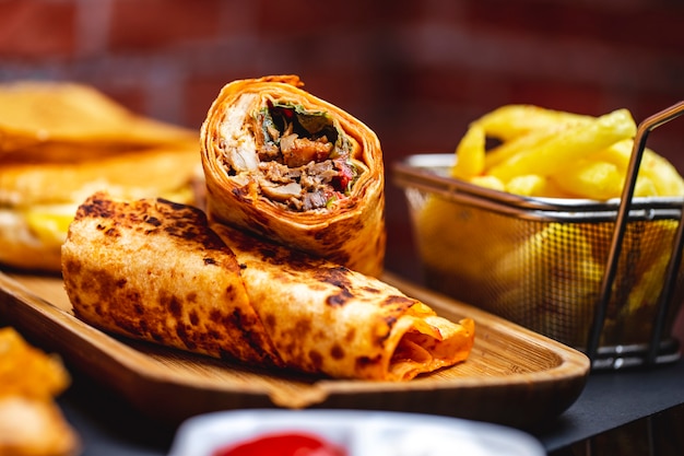 Foto grátis doner de vista lateral com frango grelhado alface tomate e batata frita em cima da mesa