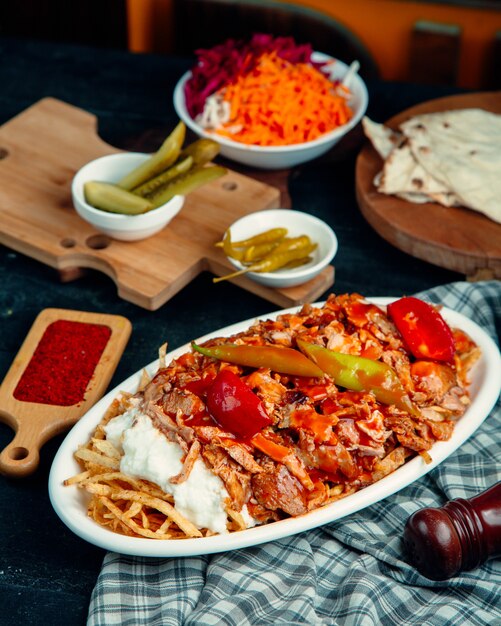 Doner kebab de cordeiro, guarnecido com tomate e pimenta, servido com batata frita e iogurte