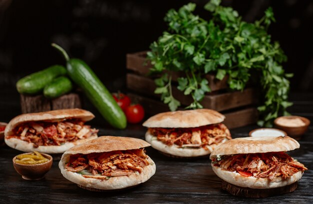 Doner turco servido dentro de pães sobre uma mesa de madeira rústica