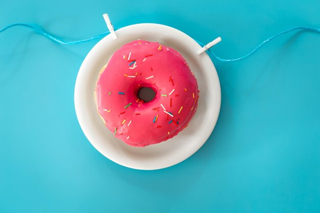 Donut em glacê rosa em um plano de fundo colorido