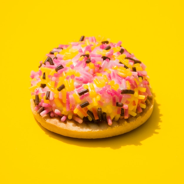 Donut embrulhado com granulado em fundo amarelo