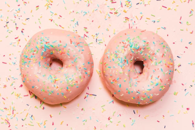 Donut fosco com granulado colorido sobre superfície rosa