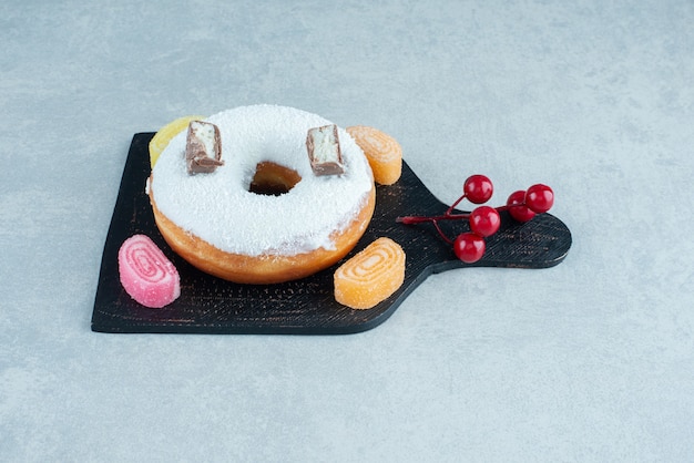 Donut glaceado e marmeladas açucaradas em uma placa de mármore.