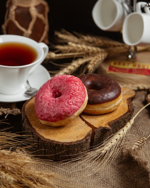 Donuts com creme vermelho e chocolate e uma xícara de chá.