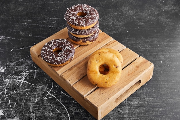 Donuts de chocolate em uma bandeja de madeira.
