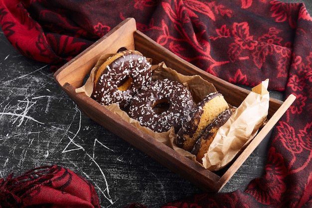 Donuts de chocolate em uma bandeja de madeira.