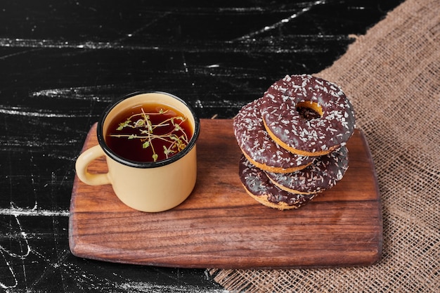 Foto grátis donuts de chocolate em uma travessa de madeira com chá.