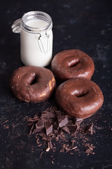 Donuts de chocolate perto da garrafa de leite e migalhas de chocolate. lanche doce.