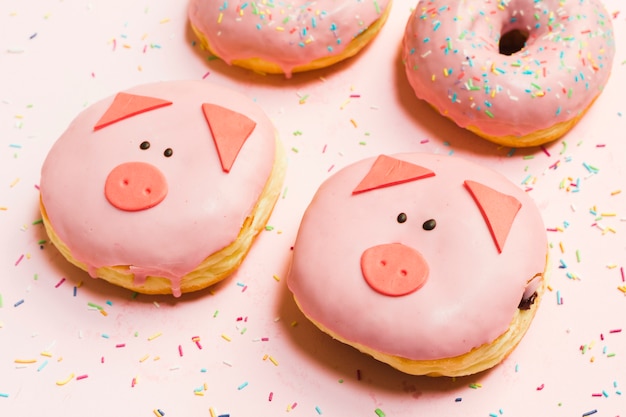 Donuts de mini porco fresco envidraçada com creme sobre o pano de fundo rosa