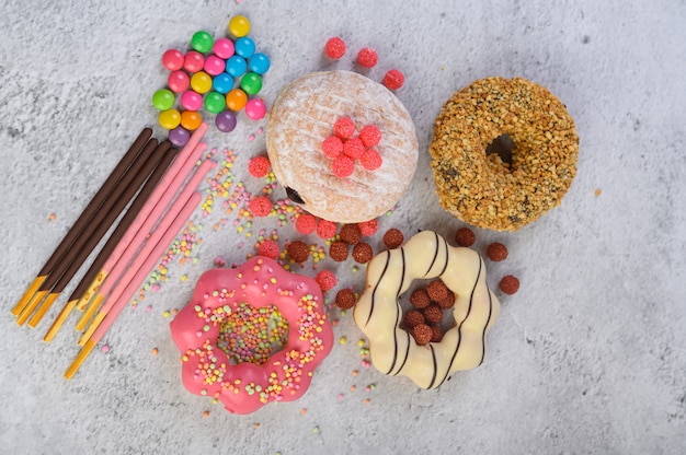 Donuts decorados glacê e granulado na vista superior de superfície branca