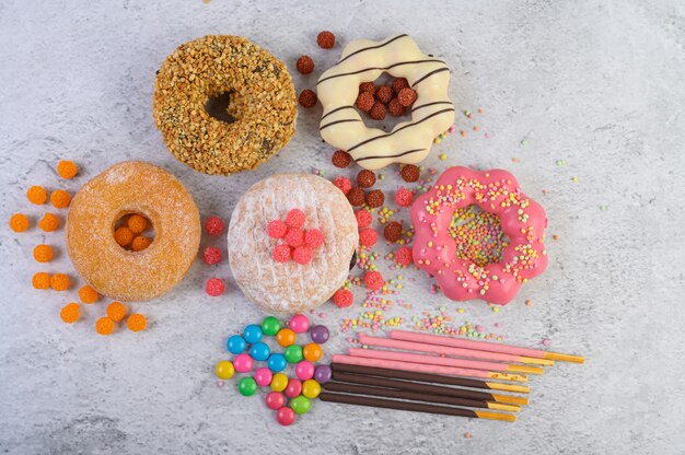 Donuts decorados glacê e granulado na vista superior de superfície branca